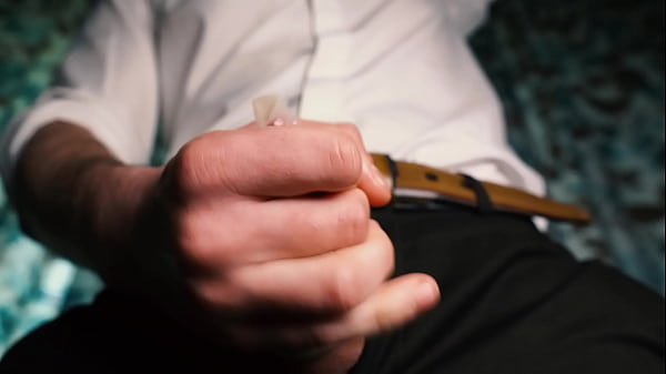 Image Sexy guy in a suit jerks off close-up, moans with pleasure and cums in a condom.