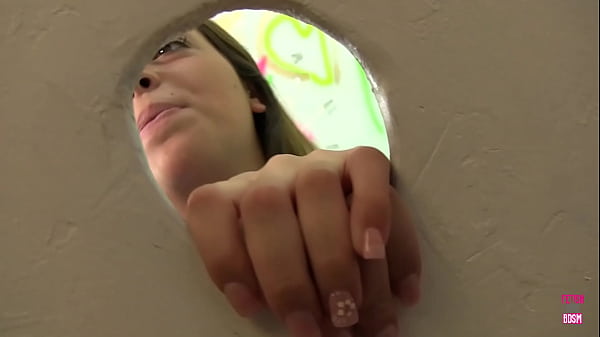 Image Eager Jenna stands in front of the glory hole waiting to drop her big cock