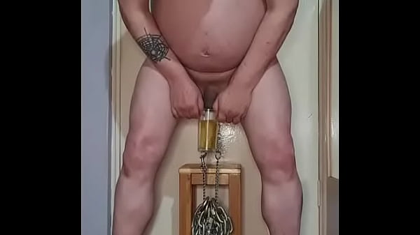 Image hanging heavy chains from my bullsacks with nipple clamps while taking a pee